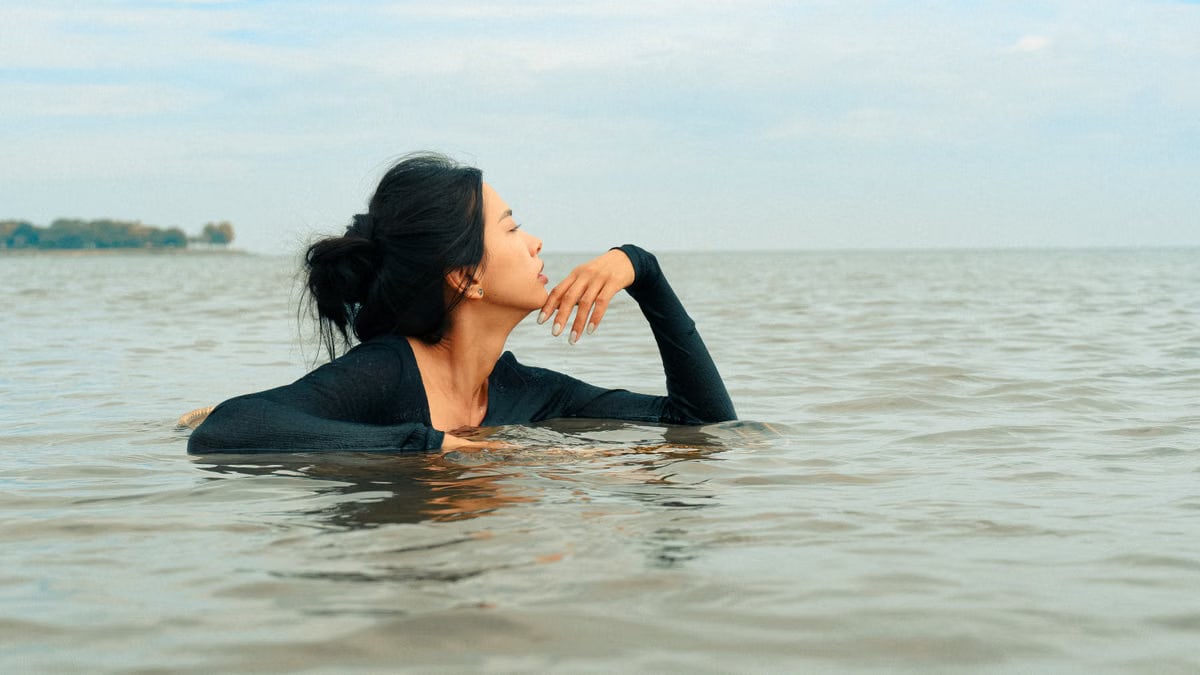 Woman posing serenely in calm lake waters, capturing a peaceful summer moment.